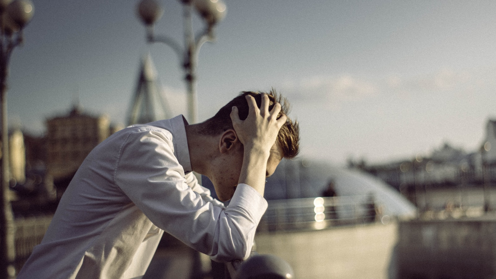 man in white dress shirt covering face with his hands